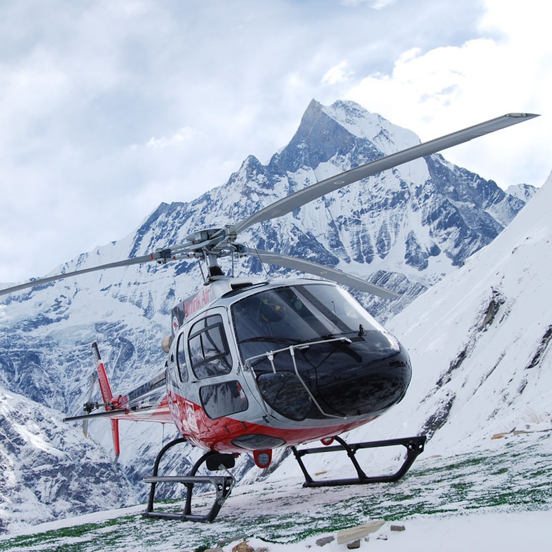 Alpine Rescue Service helicopter on snow with Himalayan peak in background